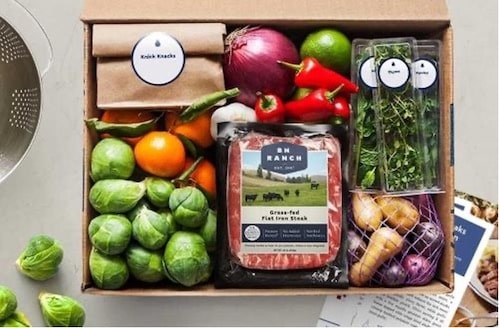 the contents of a meal delivery kit box from Blue Apron with fresh veggies, meat, and herbs