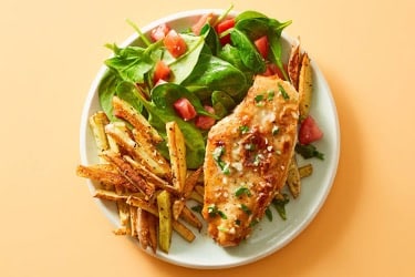 grilled chicken on a plate with fries and a fresh green salad