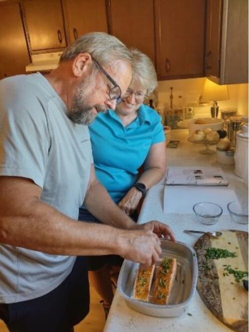 Two older adults preparing salmon in their kitchen