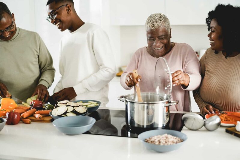A happy multigenerational black family cooks healthy dinner together