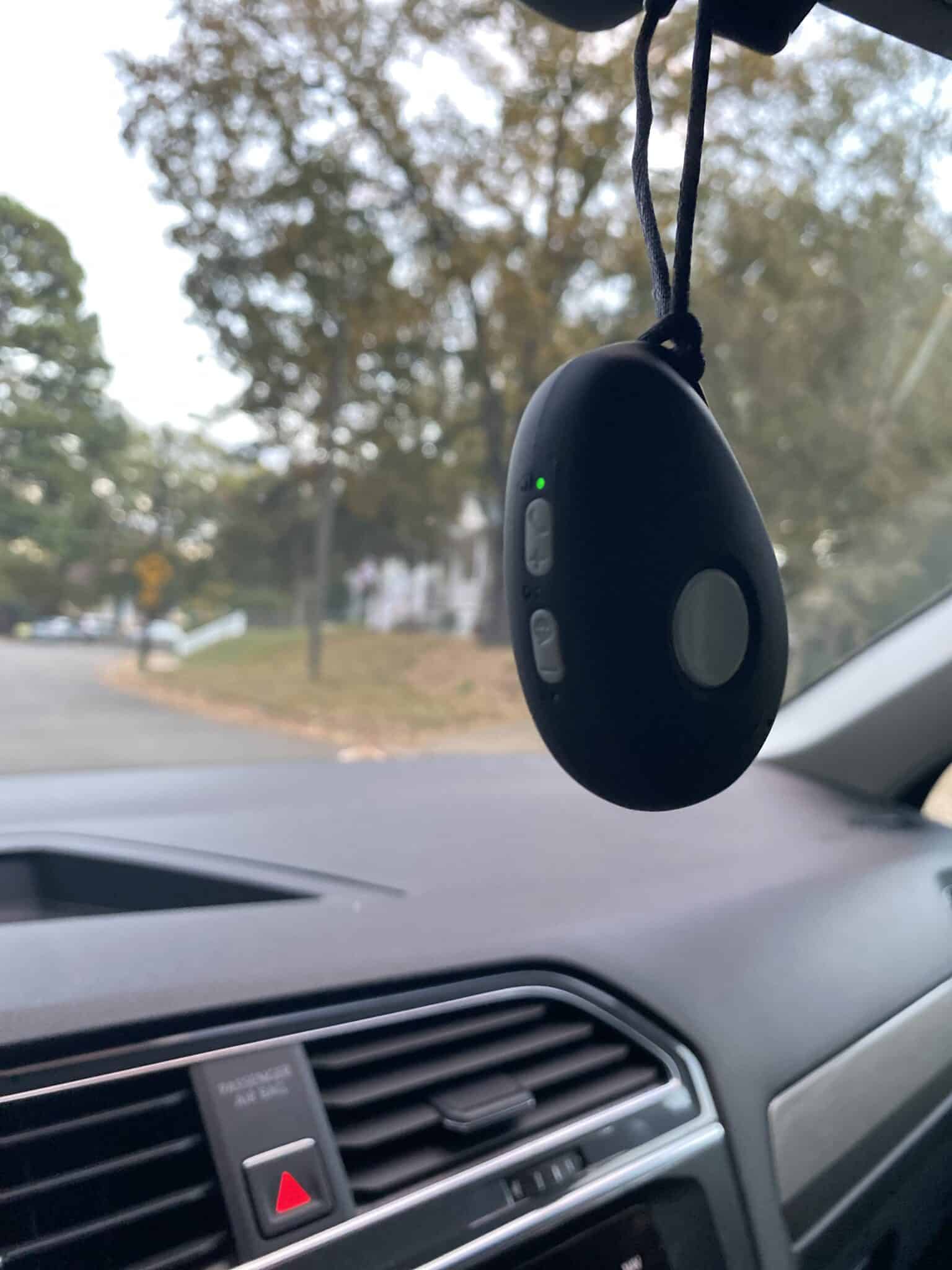 A mobile medical alert system hanging from the rearview mirror during a field test.