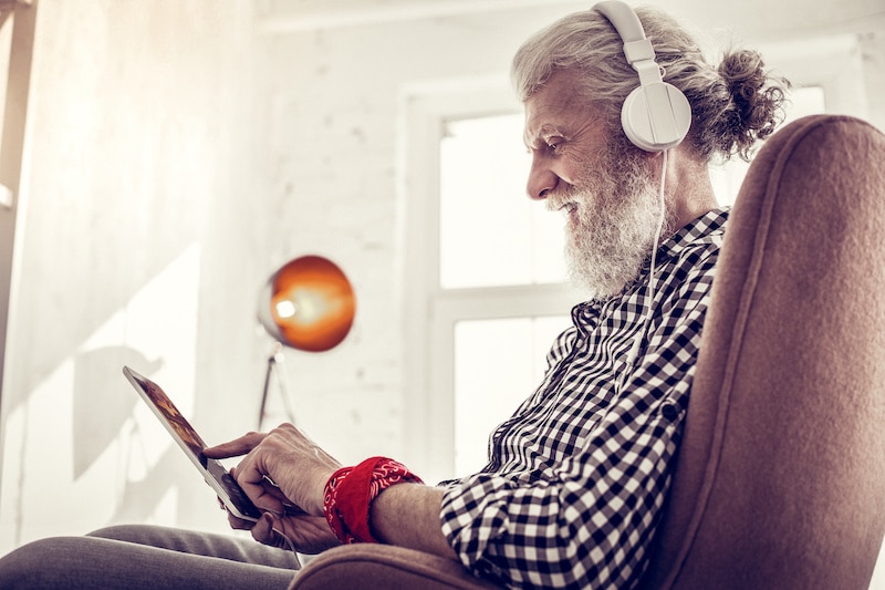 Older man with headphones using tablet