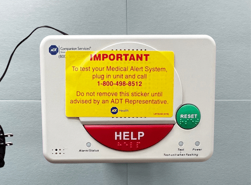 Medical alert device with large red help button on a blue background