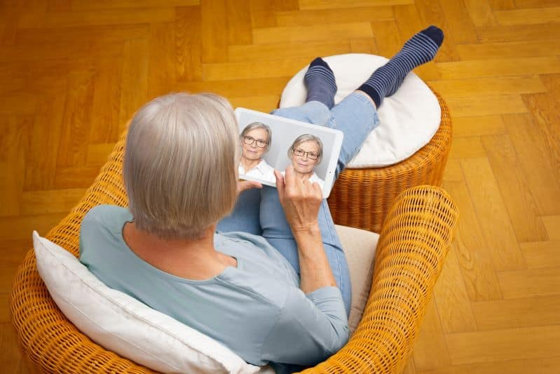 Older adult woman sitting on floor at home shopping for online glasses