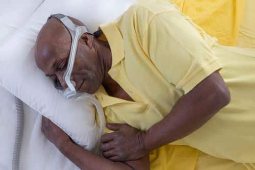Man using CPAP machine while lying down