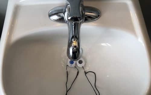 running water on two medical alert necklaces in a sink