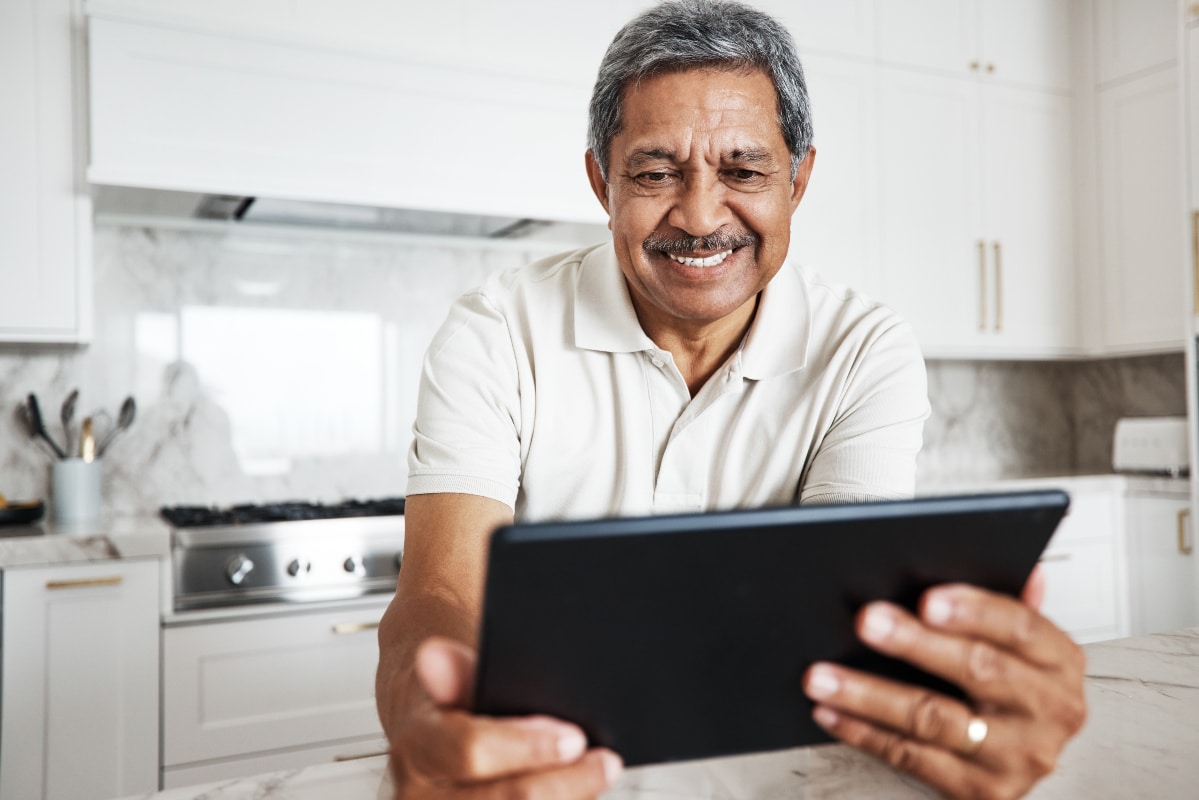 Man using tablet at home and smiling