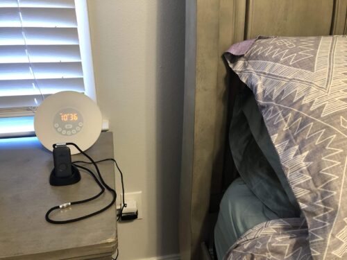 Mobile system in a charging cradle on a gray bedside table.
