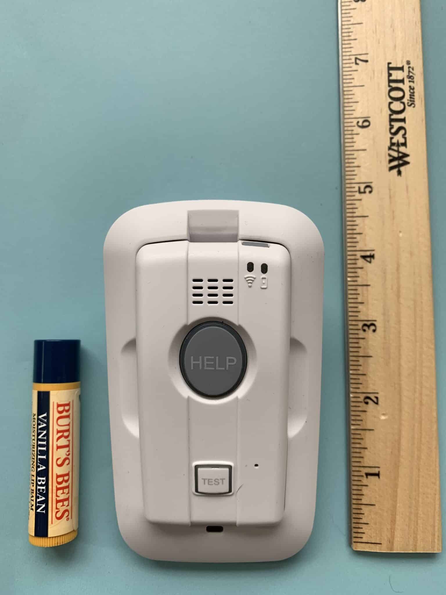 Elite 911 medical alert device next to a tube of lip balm and ruler for size comparison