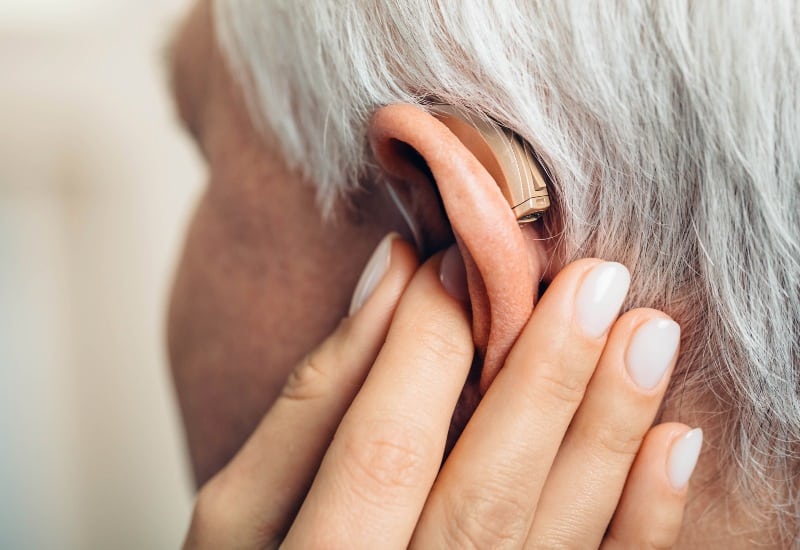 Close-up photo of an older adult having their hearing aid adjusted