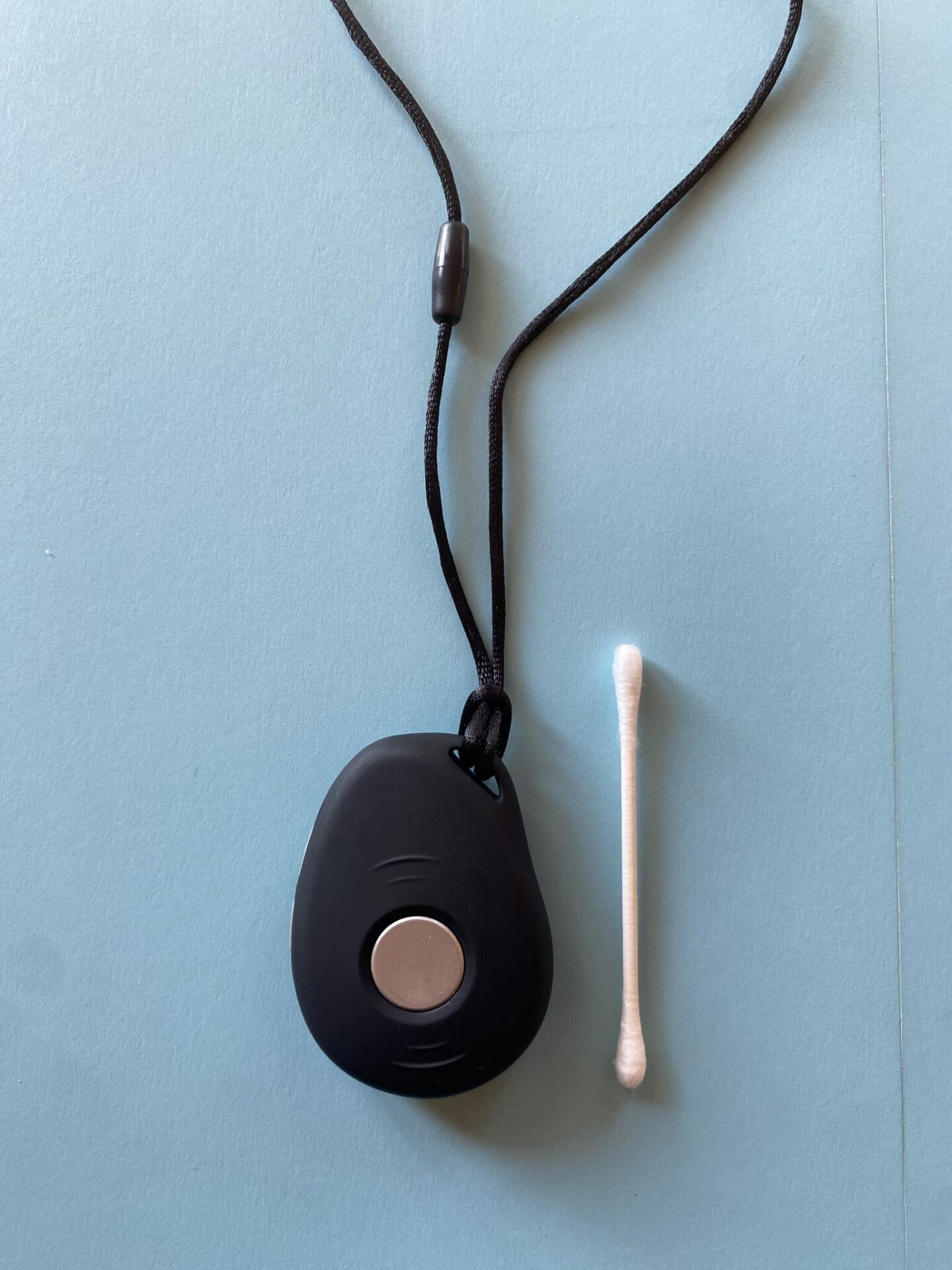 Black LifeFone VIP Active mobile system next to a Q-tip against a blue background