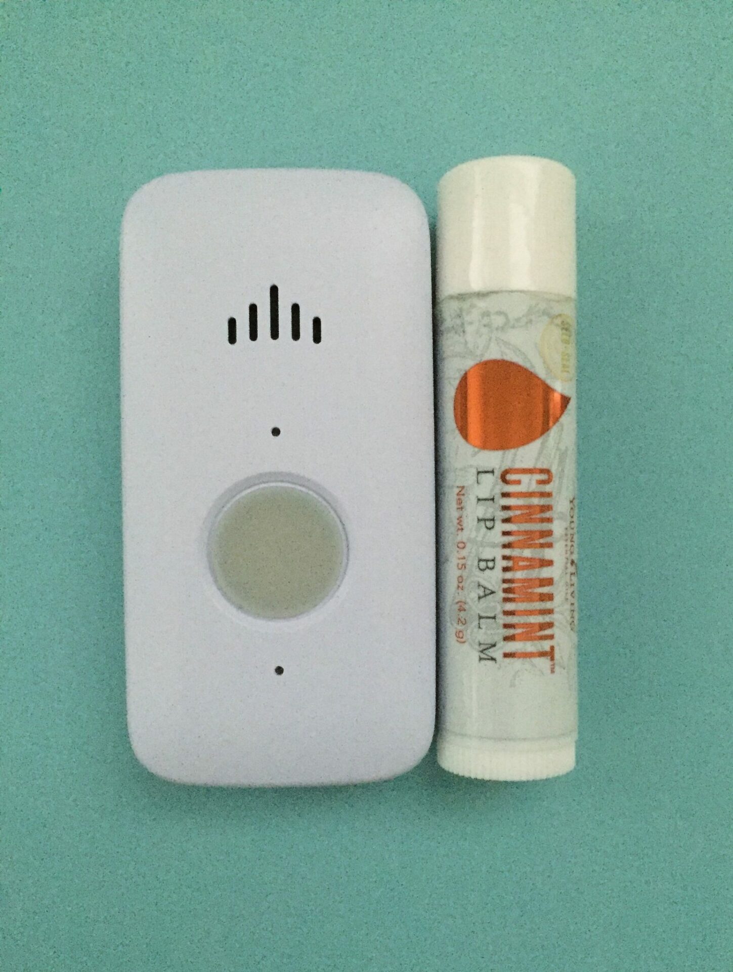 White LifeFone VIPx system next to a tube of lip balm against a blue background
