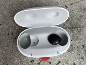 Black Signia Active hearing aid inside its white charging case