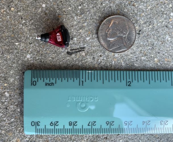 Signia Silk X compared to the size of a nickel and measured next to a blue ruler