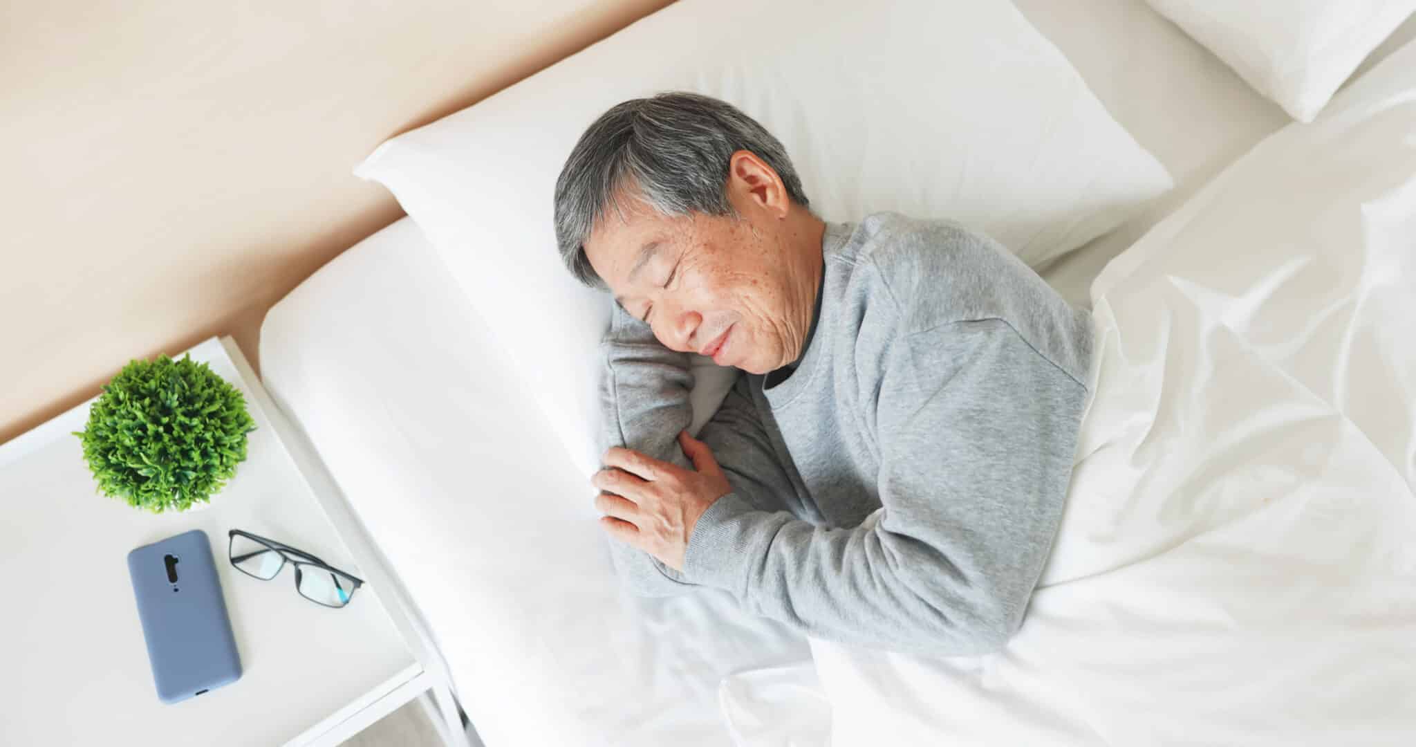 Older adult sleeping in bed at home smiling