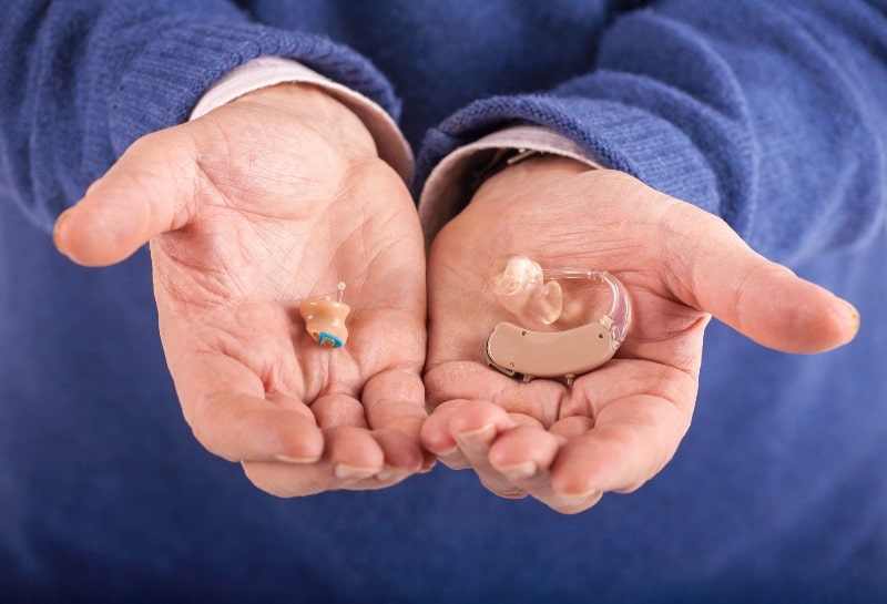 Hands outstretched holding hearing aids