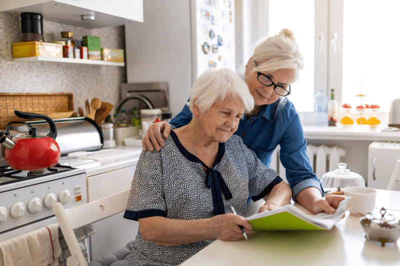 Caregiver sitting at kitchen counter with senior woman