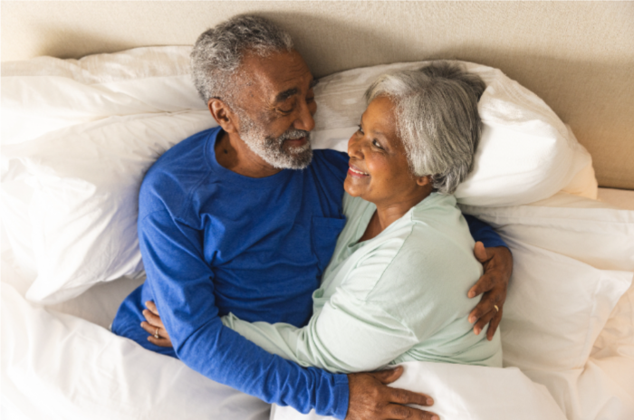 Smiling couple embrace each other in bed