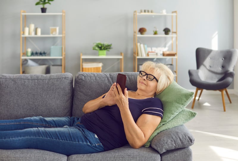 Older adult on a sofa looking at a smartphone device