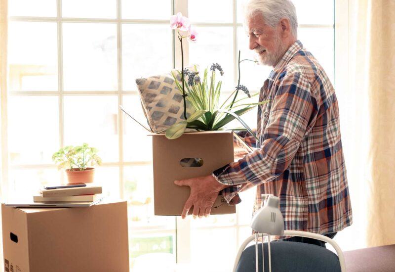 older independent man moves boxes around his home