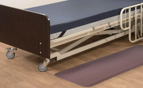 Floor mat placed next to a hospital bed | CAPTION: Floor mats are placed on the floor during the night, but should be moved away during the day to avoid tripping.