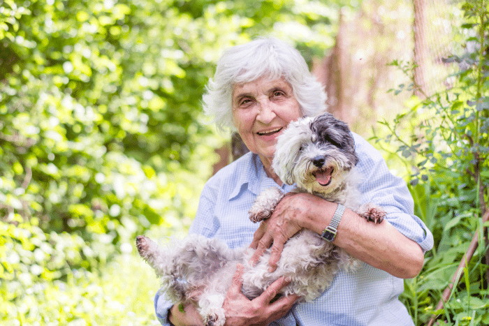 older woman holding her dog outside