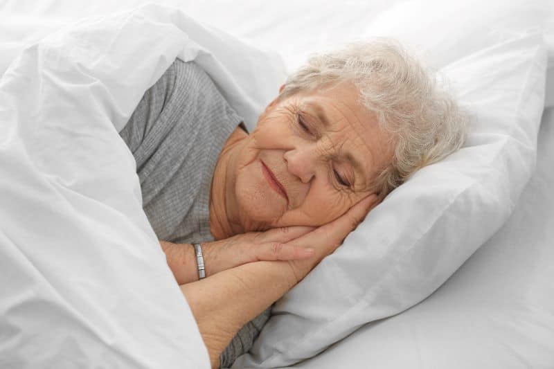older adult woman smiling and sleeping