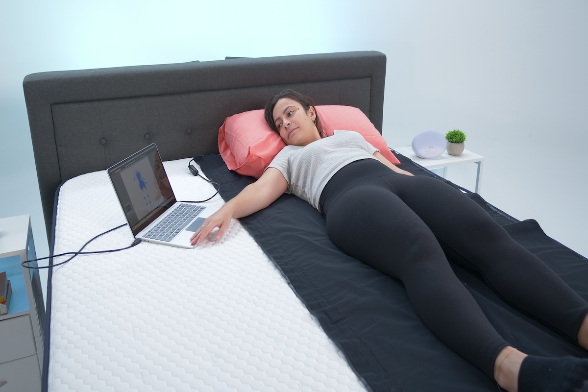 A mattress tester lies on her back while analyzing pressure map results for the Brooklyn Bedding Aurora Luxe