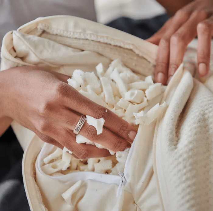 A hand removing shredded latex from Naturepedic Organic Adjustable Latex Pillow