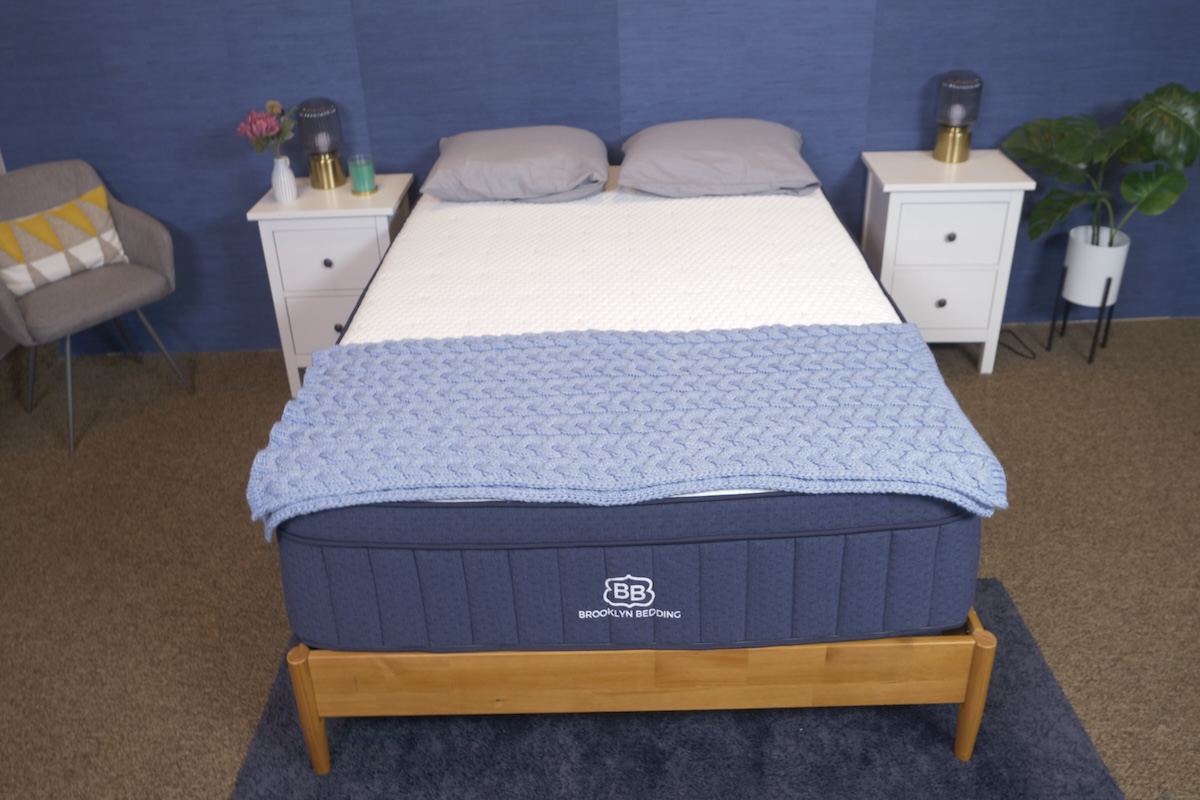  Blue and white Brooklyn Bedding Aurora Luxe Cooling mattress with a blue knit blanket and gray pillows