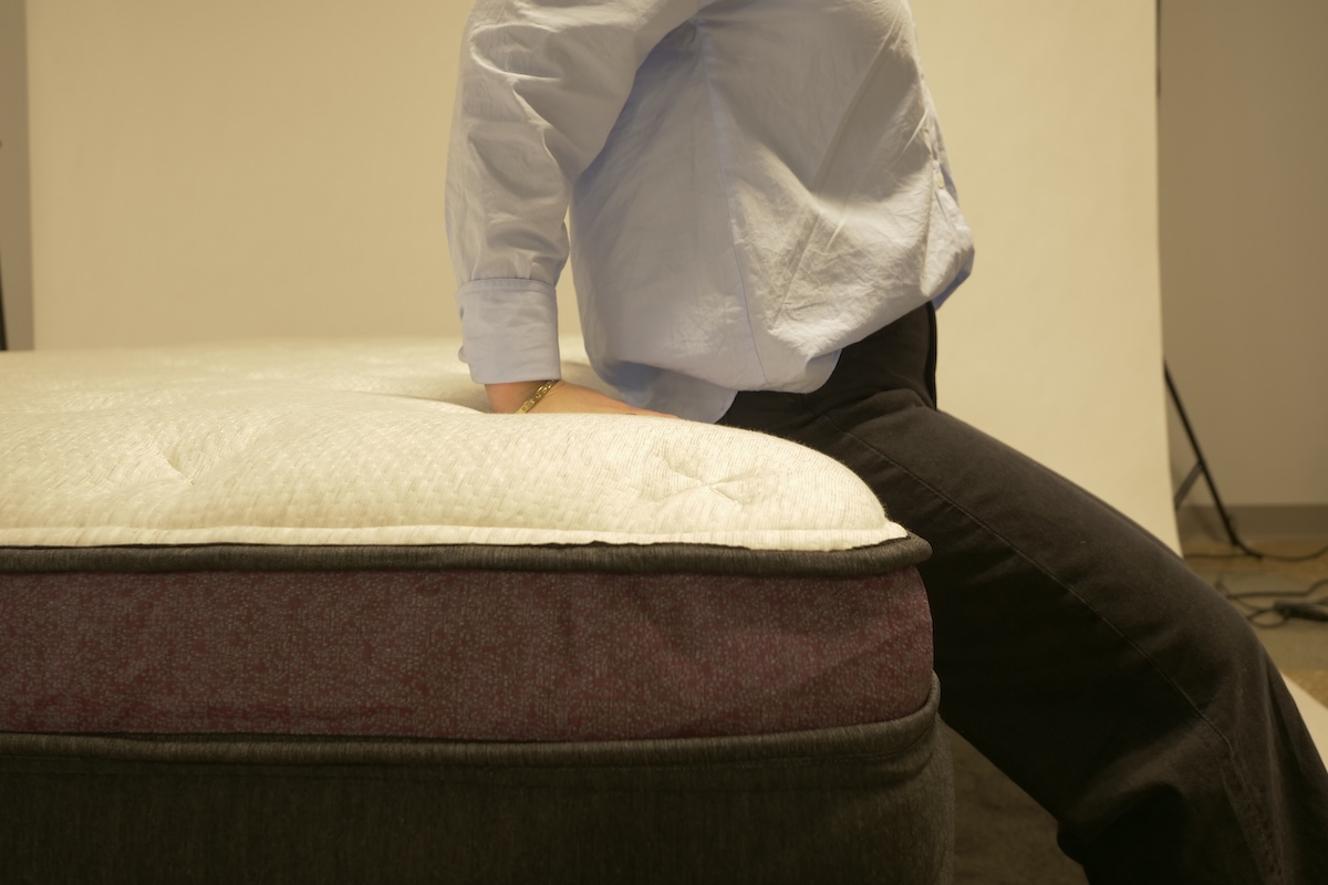 Person sitting on the edge of a Helix mattress