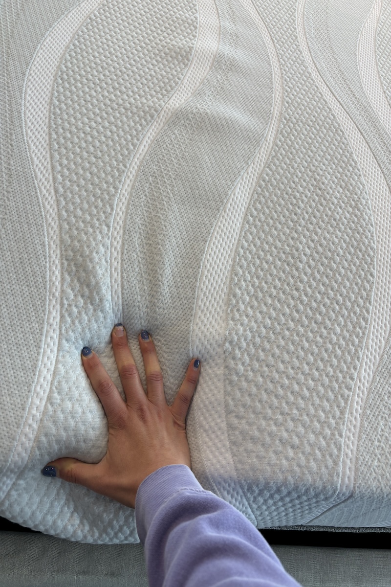 Woman’s hand pressing into the surface of the Sleep Number m7 memory foam mattress