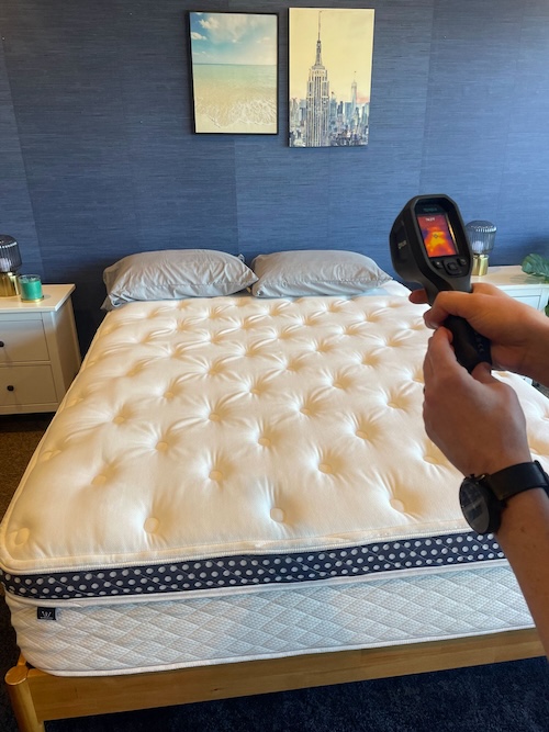  A person pointing a temperature gun at a mattress 