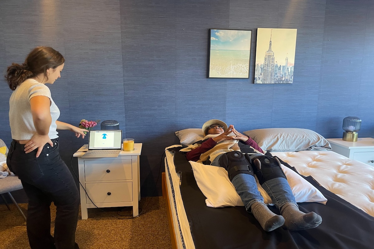 Woman lying on a pressure map on a mattress and tester reading results on a laptop