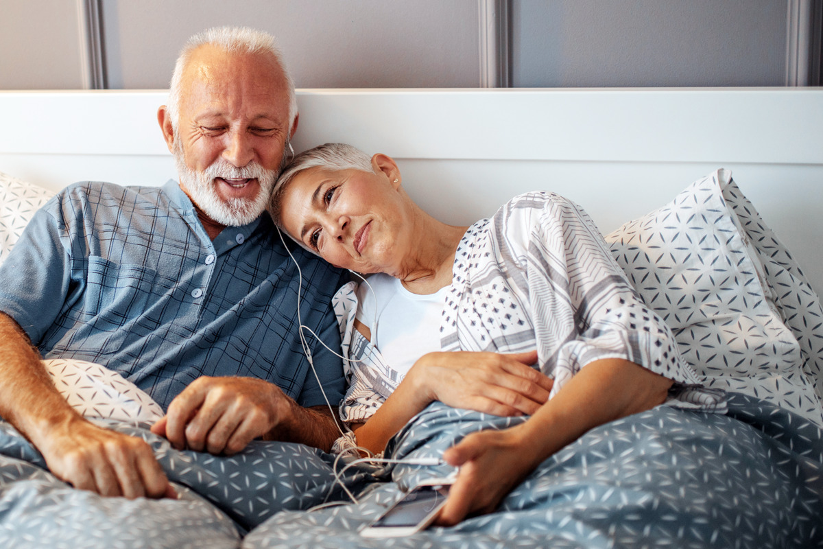 Image of an older couple listening to music in bed